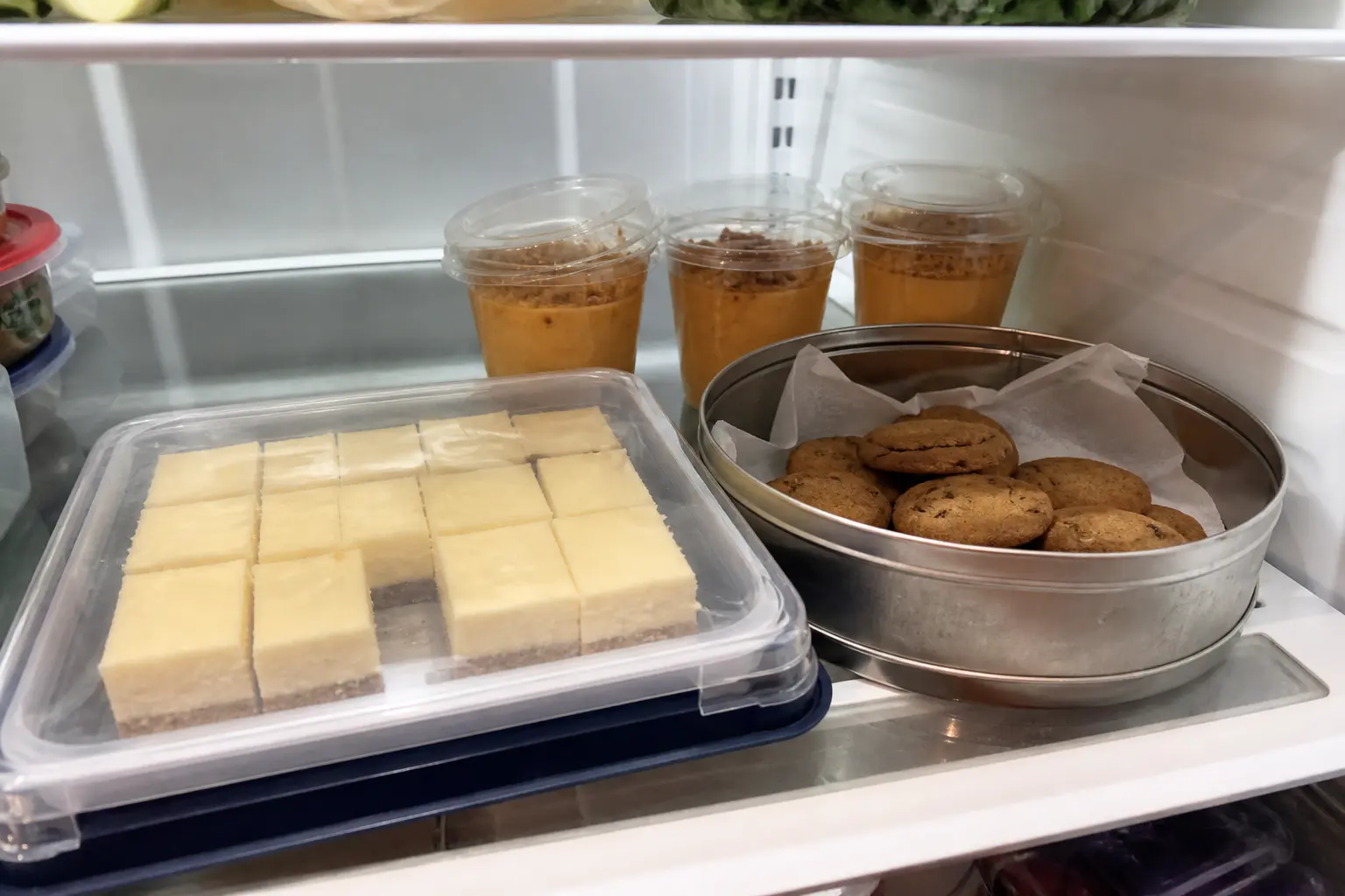 Make-ahead Thanksgiving cheesecake bars, cookies, and mousse cups stored in the refrigerator.