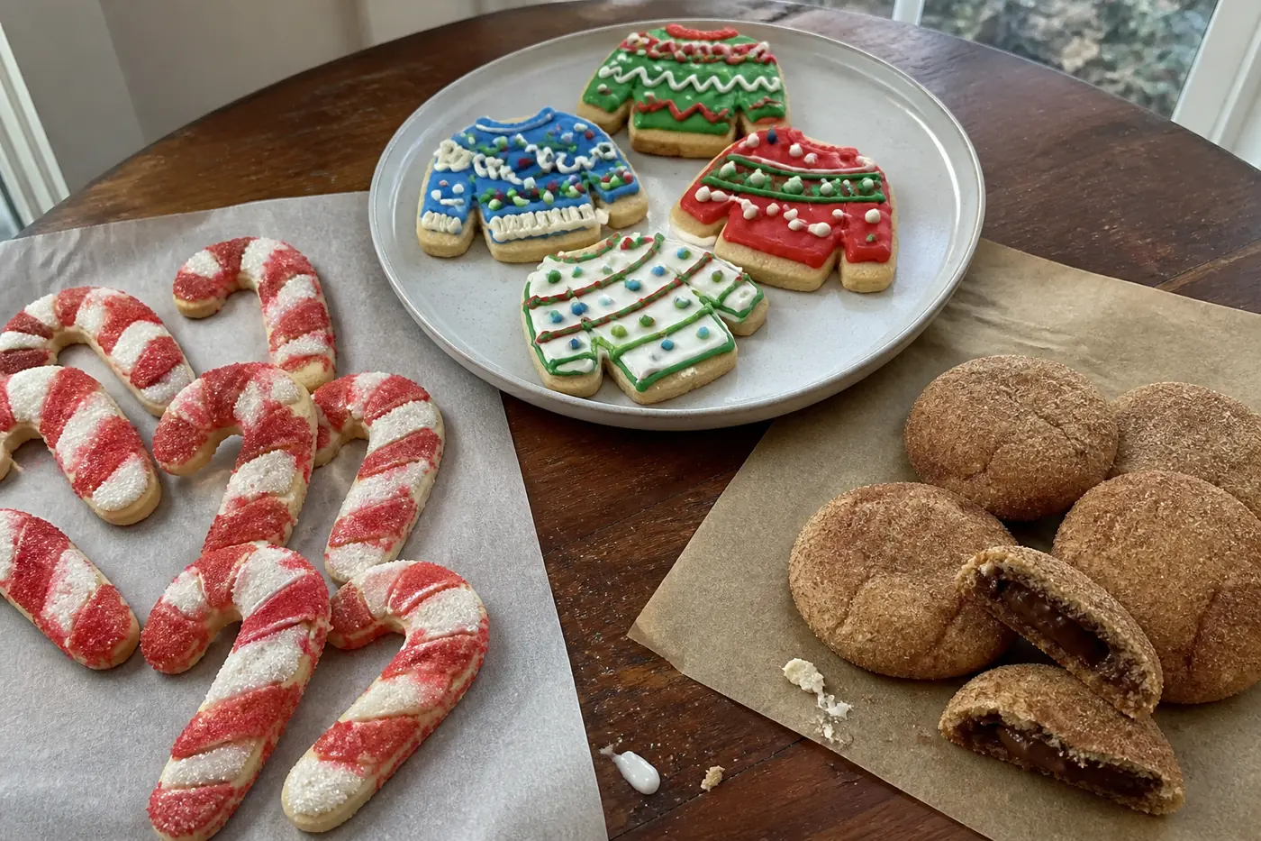 Candy cane cookies, ugly sweater cookies, and chocolate-filled cinnamon cookies arranged for a Christmas cookie swap.