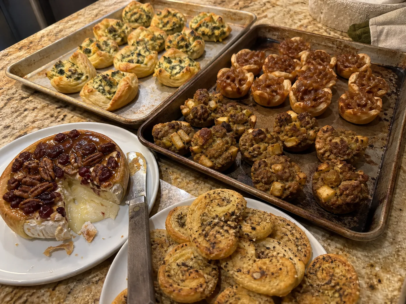 Cranberry pecan baked brie, onion tartlets, stuffing bites, spinach artichoke pastry cups, and Parmesan herb palmiers