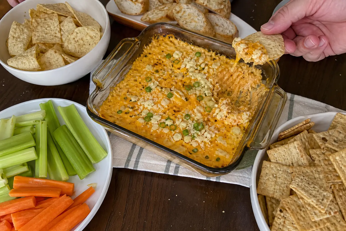Buffalo chicken dip served with celery, carrots, tortilla chips, crackers, and toasted baguette slices