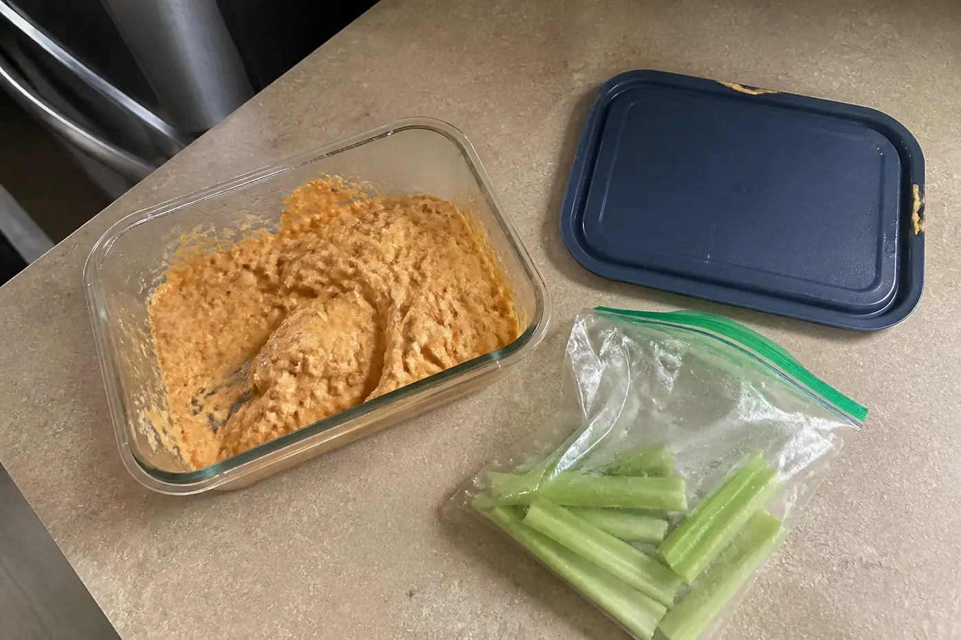 Leftover buffalo chicken dip stored in a glass container with a lid for reheating