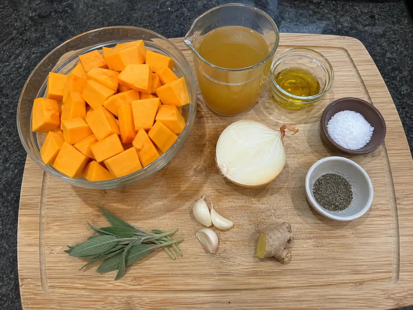 Butternut squash soup ingredients with cubed squash, onion, garlic, sage, ginger, broth, and olive oil