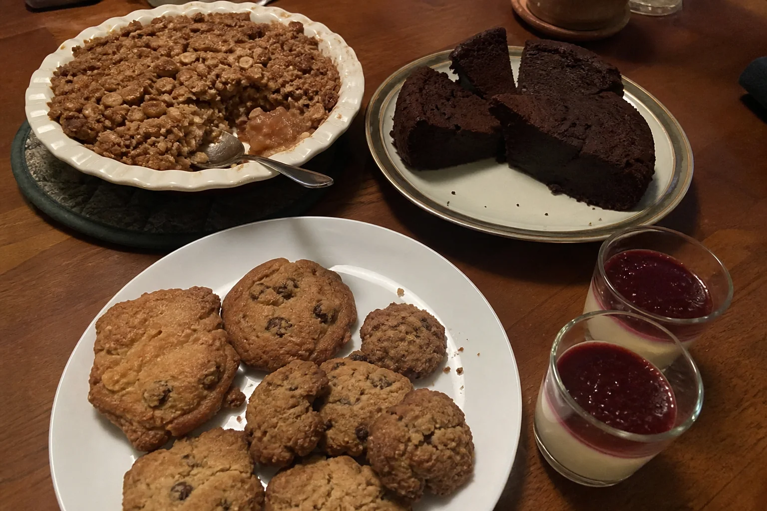 Make-ahead Christmas dessert platter with cookies, apple crisp, chocolate cake slices, and panna cotta.