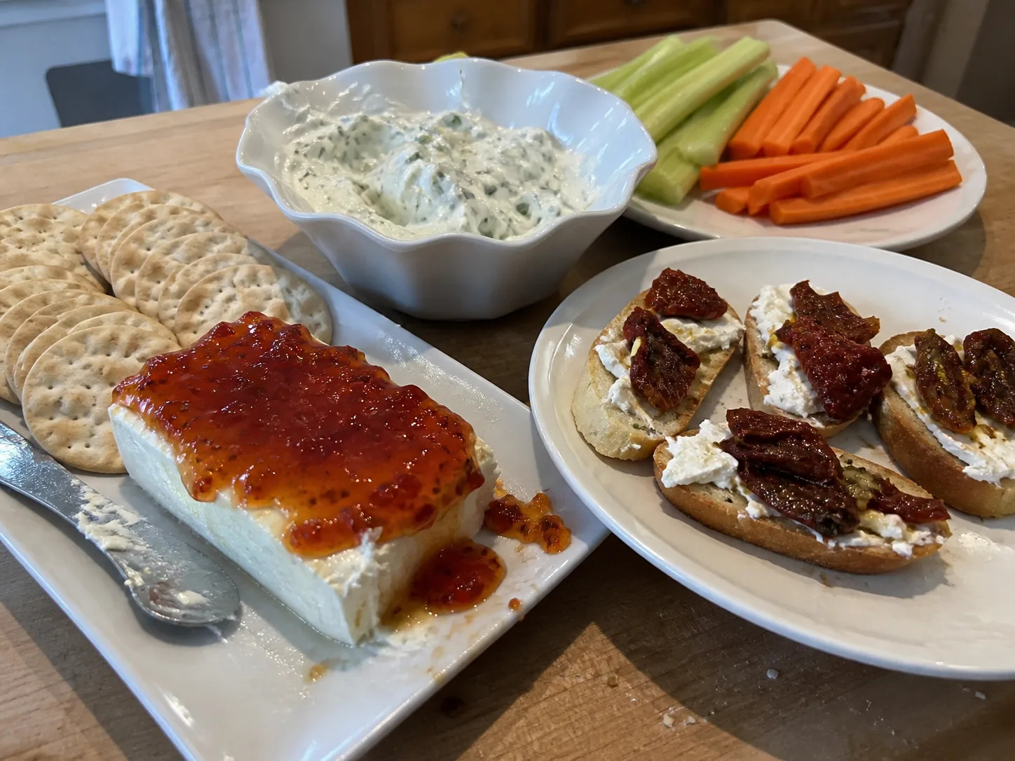 Pepper jelly cream cheese, garlic herb spread, vegetable sticks, crackers, and sun-dried tomato crostini.