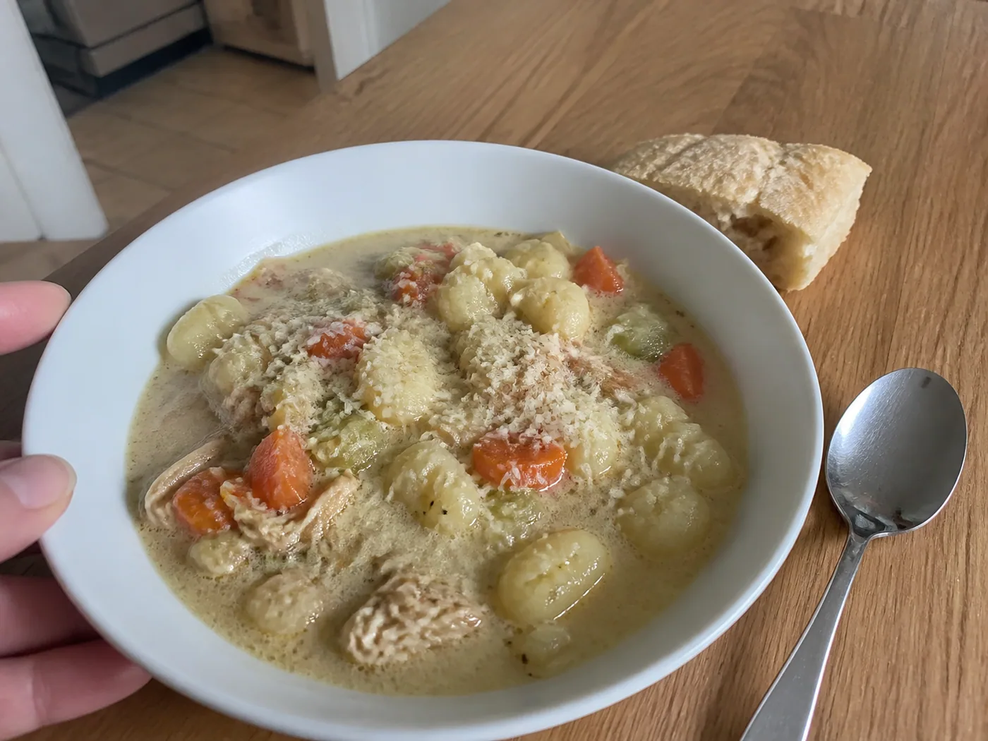 Creamy crockpot chicken gnocchi soup with carrots, celery, Parmesan, and bread.