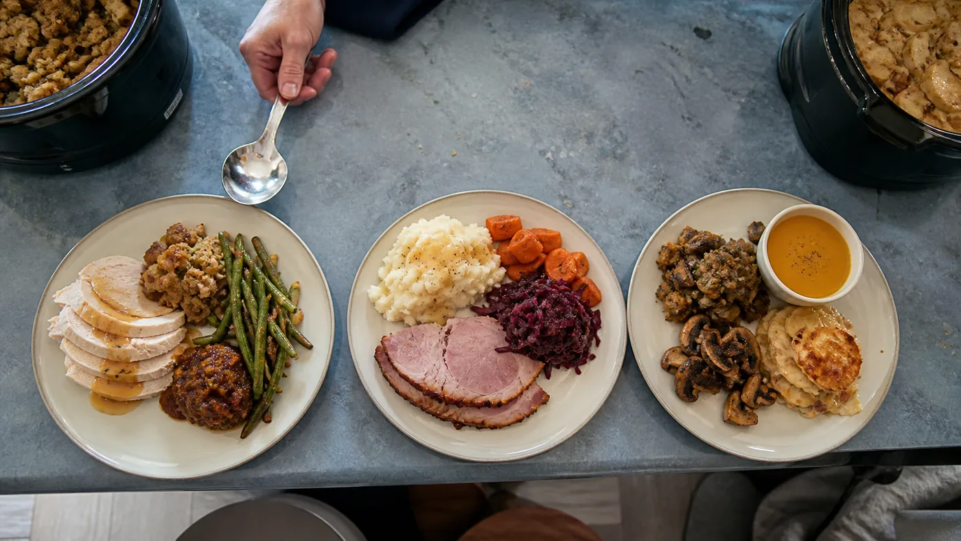 Three Crockpot Thanksgiving menu plates with turkey, stuffing, potatoes, vegetables, soup, and chutney.