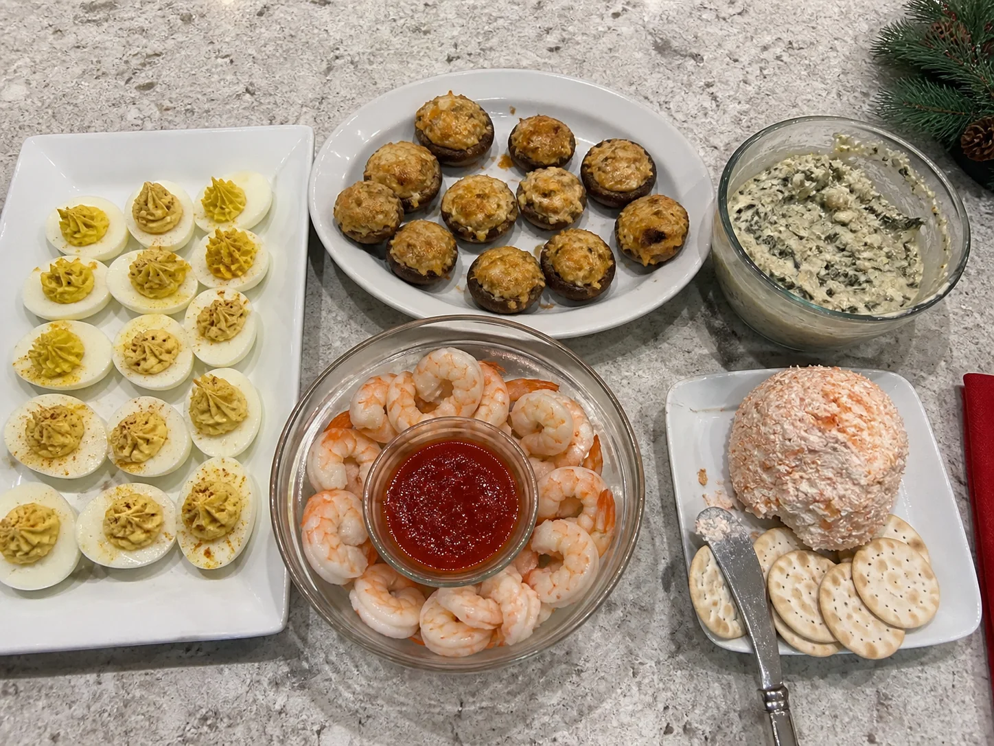 Christmas appetizer spread with deviled eggs, stuffed mushrooms, shrimp cocktail, spinach artichoke dip, and a smoked salmon cheese ball.
