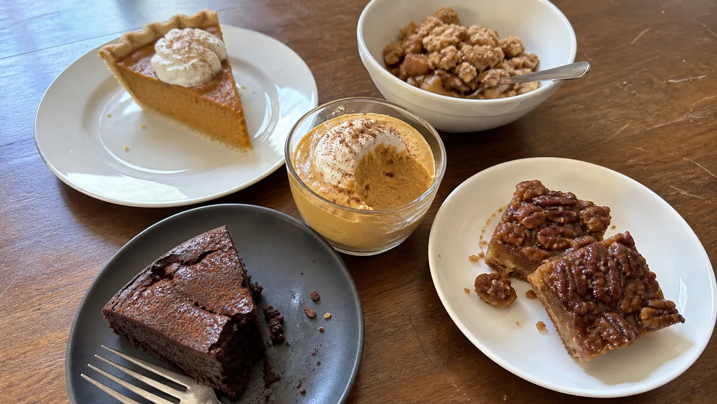 Pumpkin pie slice, apple crisp, flourless chocolate cake, pumpkin mousse, and pecan bar arranged as easy gluten-free Thanksgiving dessert choices.