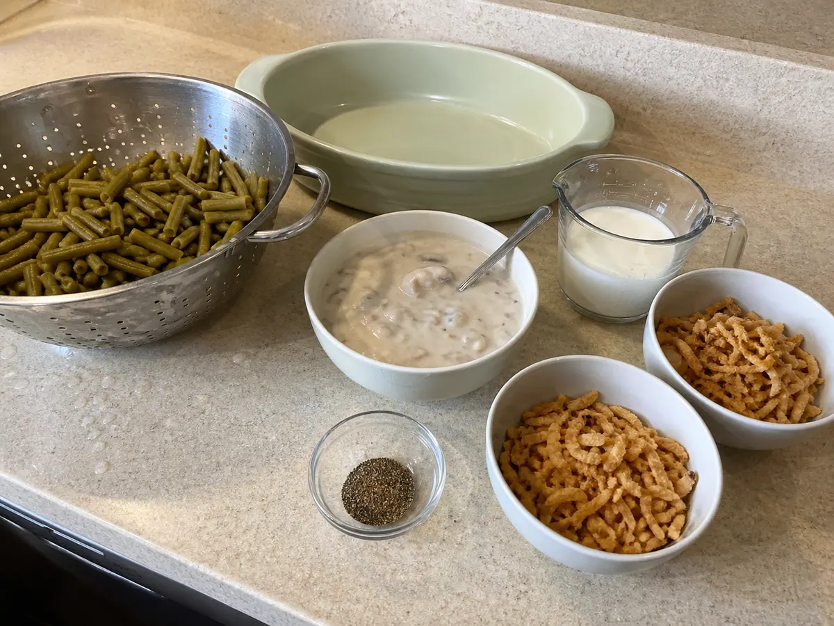 Canned green beans, cream of mushroom soup, milk, pepper, and crispy fried onions for green bean casserole.
