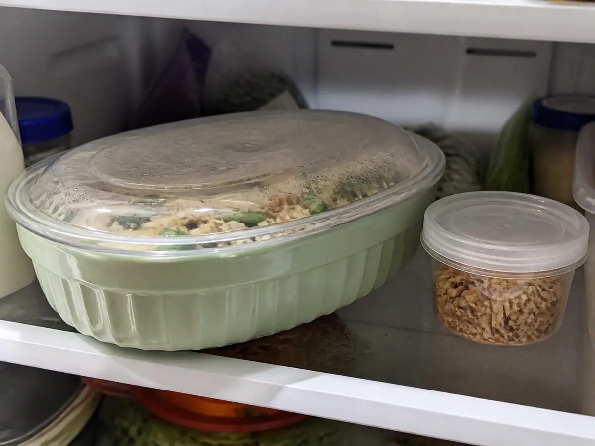 Prepared green bean casserole filling covered in a baking dish with fried onions kept separate for later.