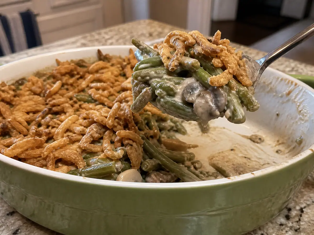Spoonful of creamy green bean casserole showing tender beans and crisp fried onions.