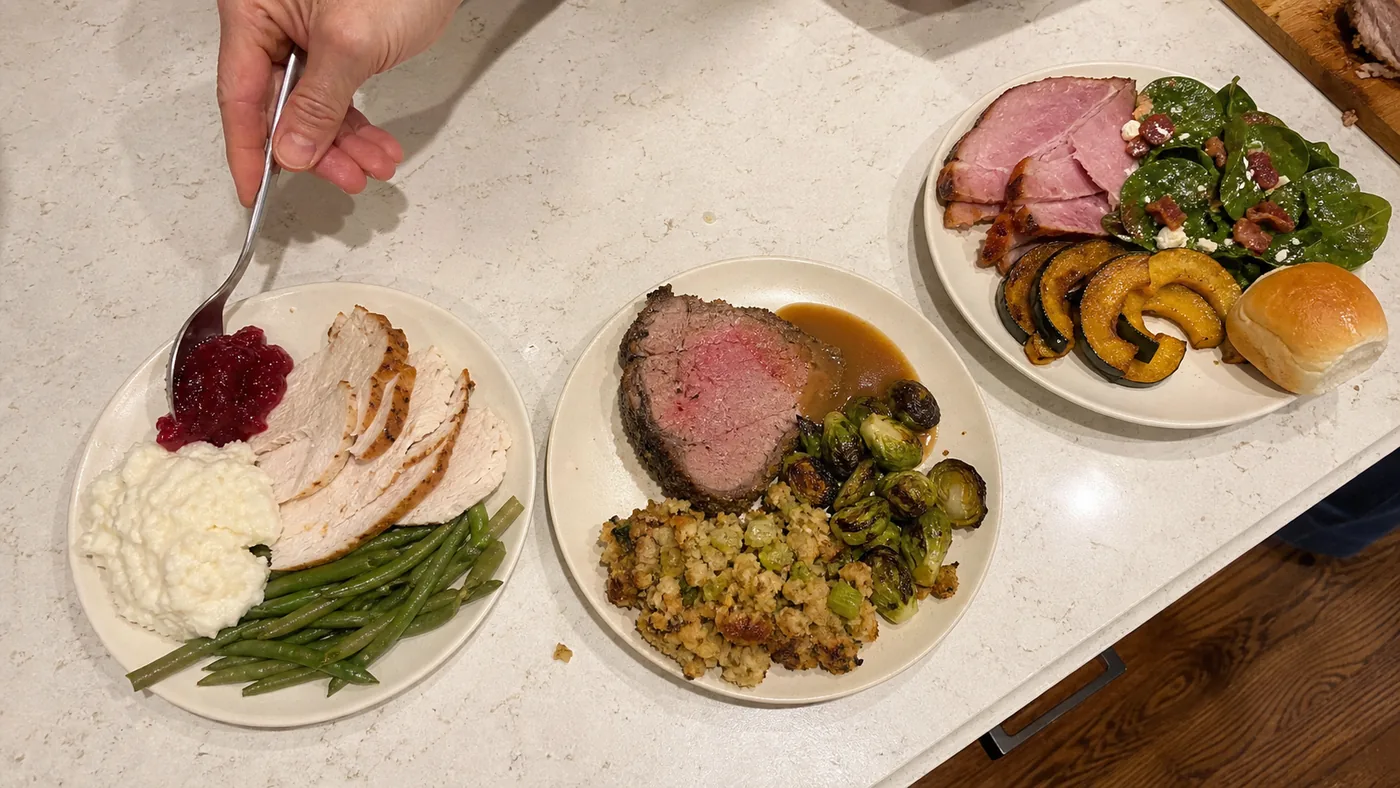 Three low-carb Thanksgiving menu plates with turkey, roast beef, vegetables, stuffing, cauliflower mash, and cranberry sauce