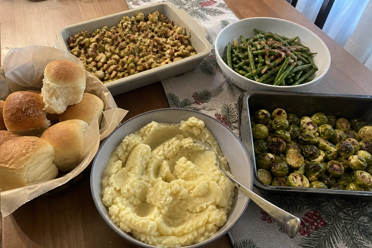Christmas side dishes including mashed potatoes, green beans, roasted Brussels sprouts, stuffing, and dinner rolls.