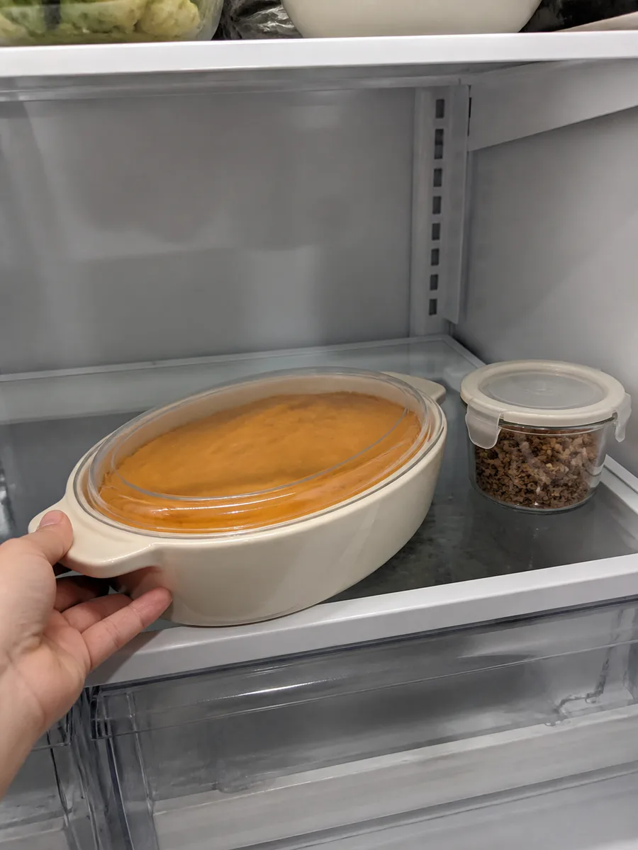 Prepared sweet potato casserole base covered in the refrigerator with pecan streusel stored separately
