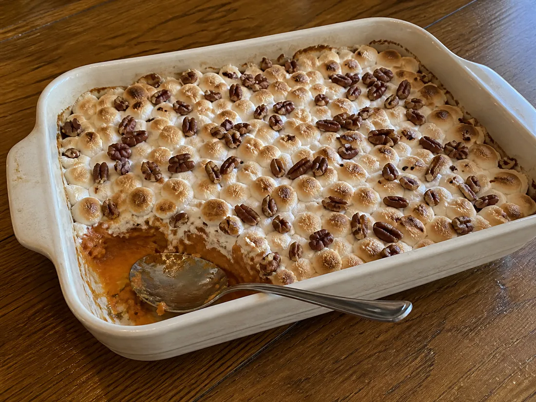 Baked sweet potato casserole topped with toasted mini marshmallows and chopped pecans
