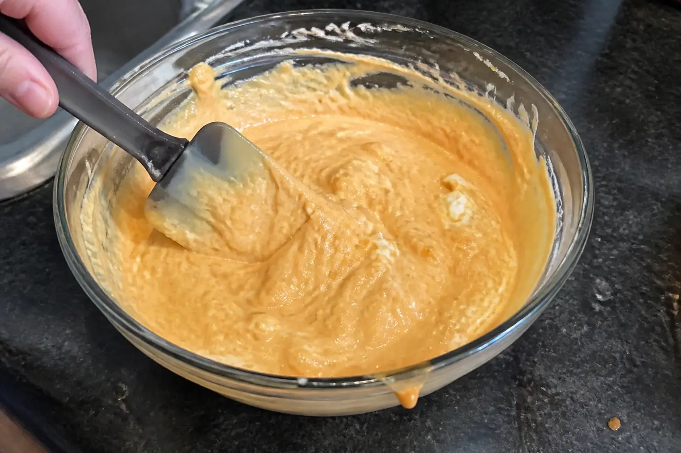 Cream cheese, ranch, and buffalo wing sauce being mixed in a bowl for buffalo chicken dip