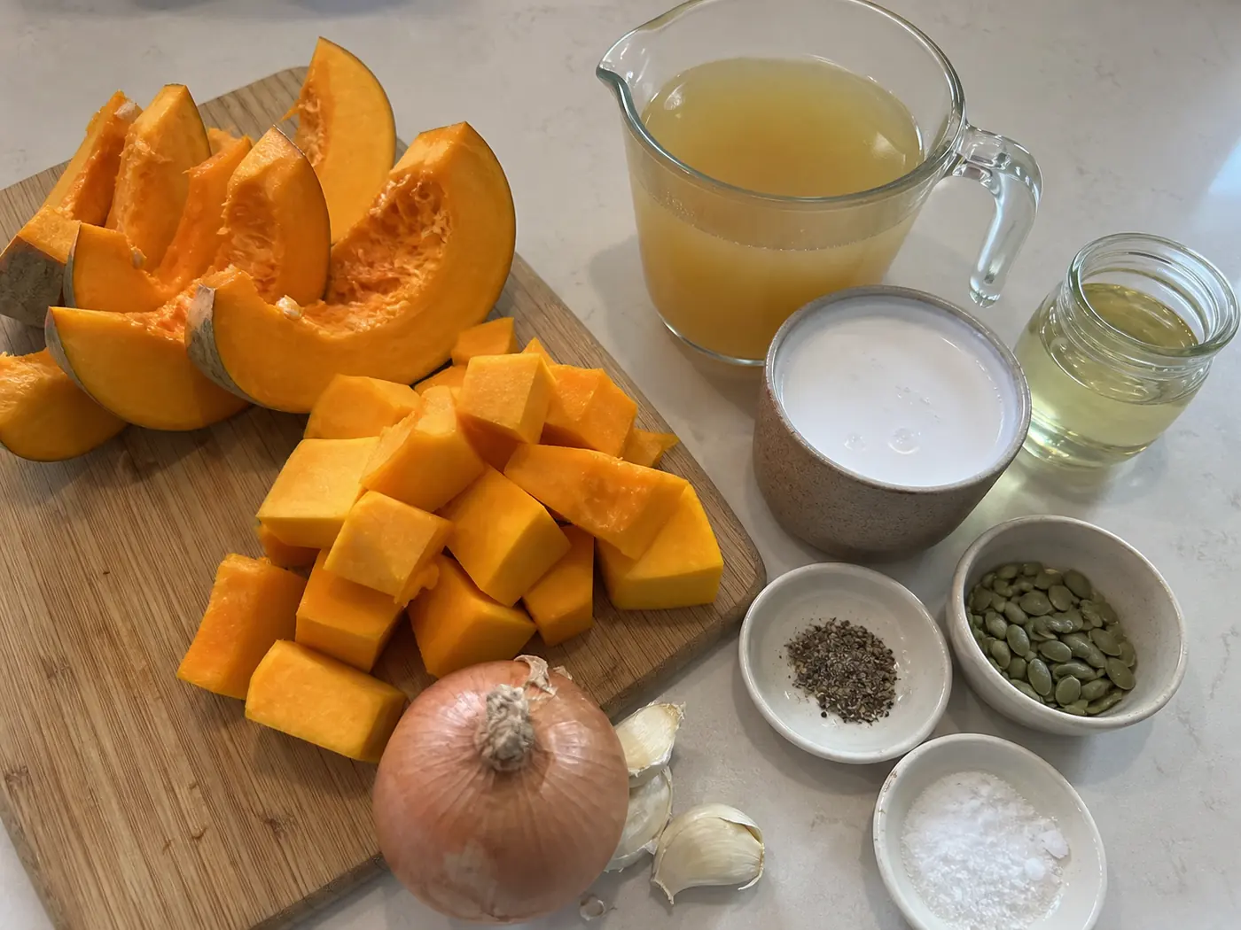Pumpkin soup ingredients including edible pumpkin, butternut squash, onion, garlic, broth, coconut milk, and pepitas
