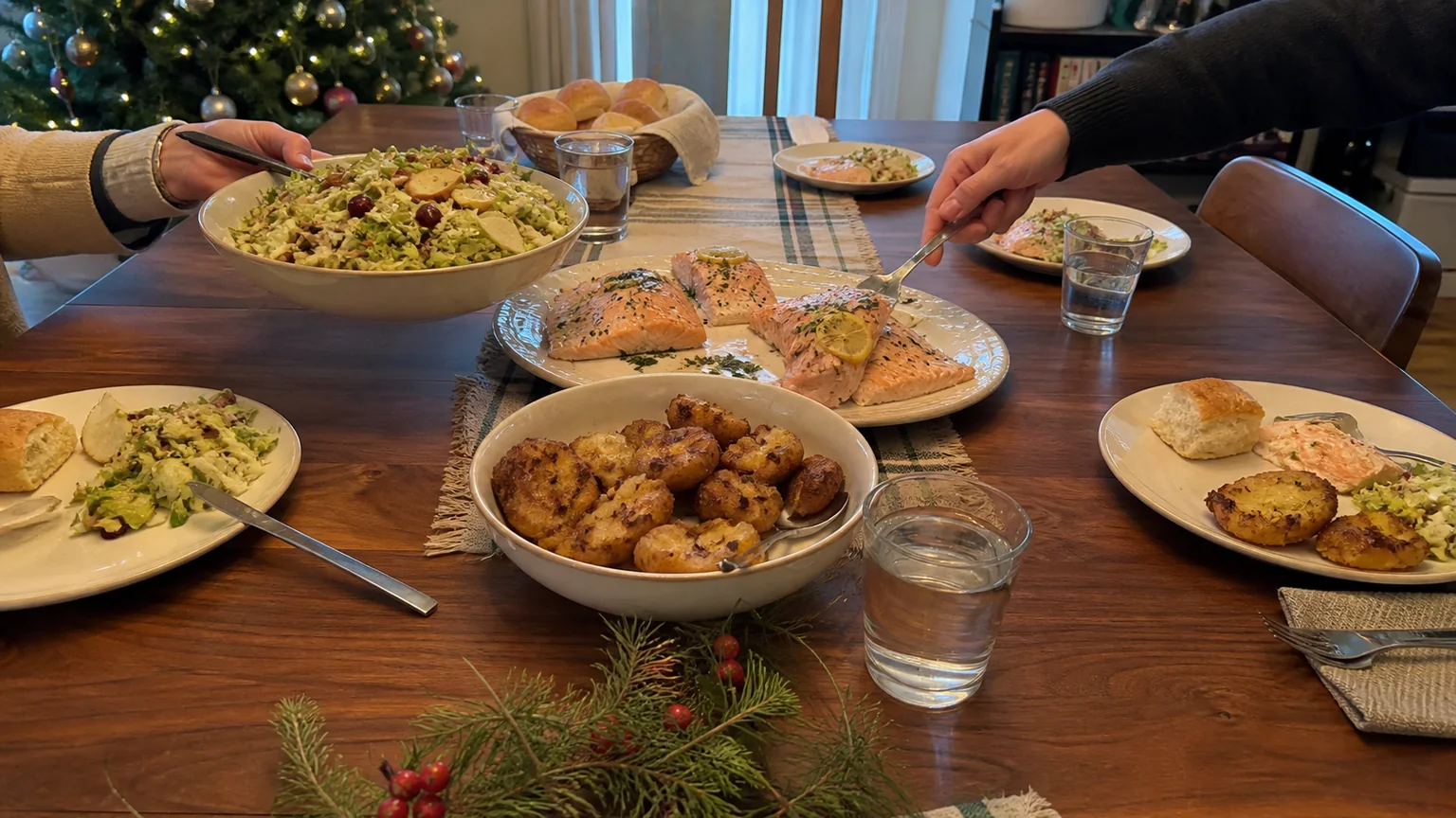 Small Christmas dinner for four with baked salmon, smashed potatoes, winter salad, and simple place settings.
