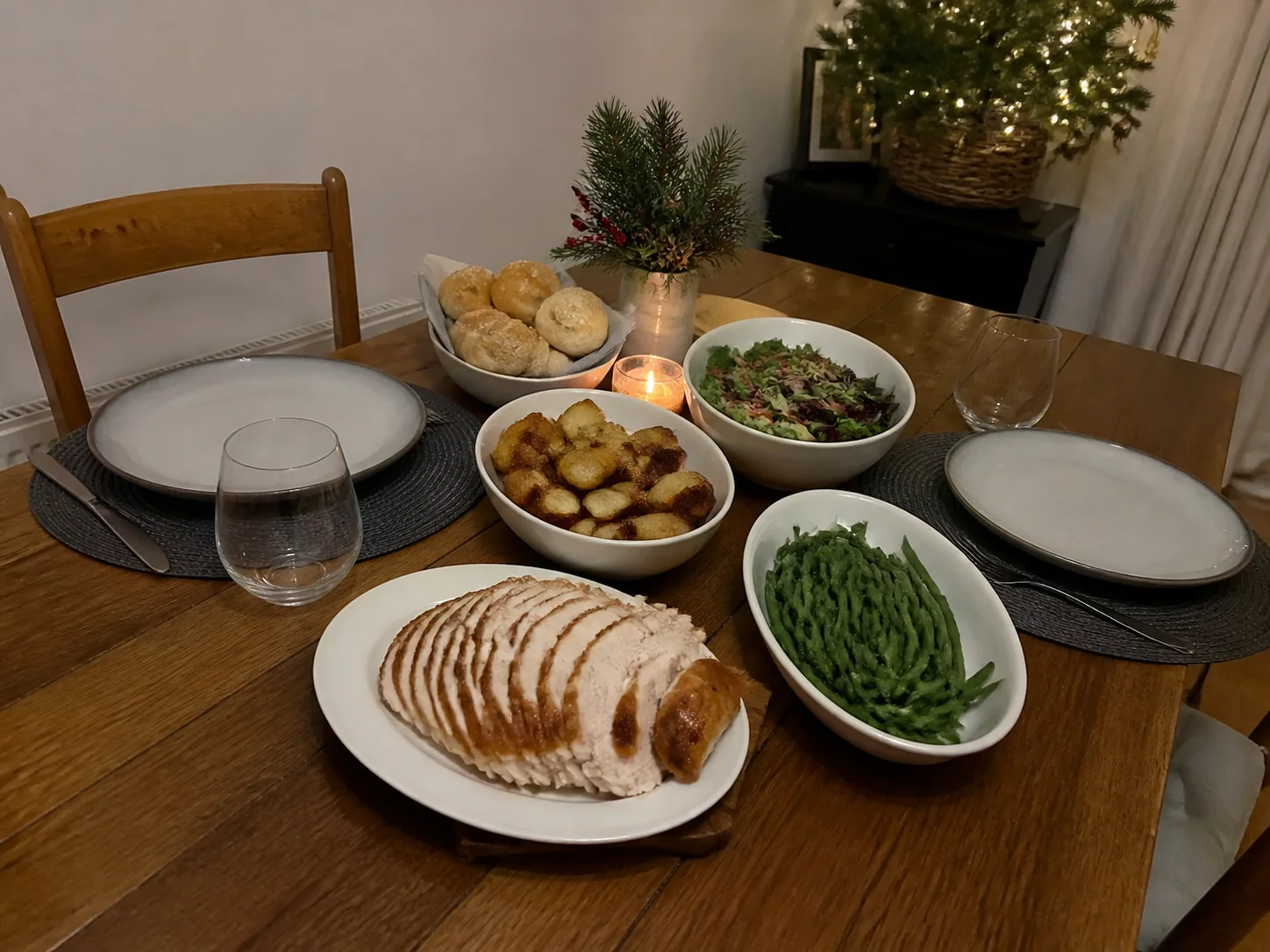 Small family Christmas dinner with roasted turkey breast, potatoes, green beans, salad, and two place settings.