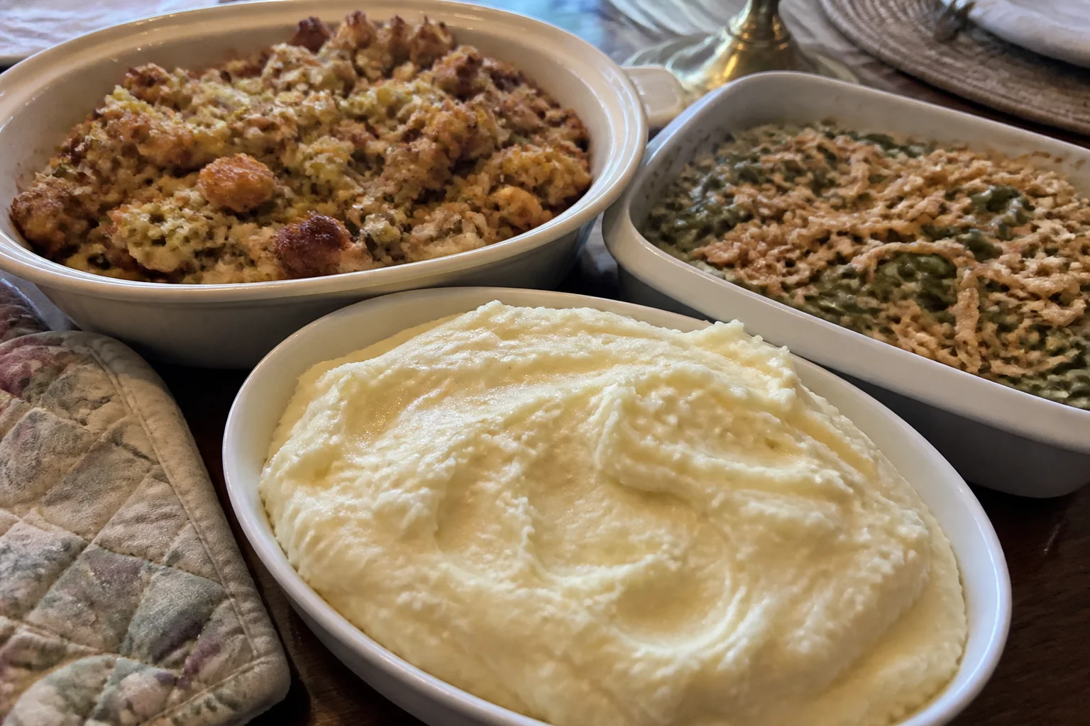 Creamy mashed potatoes, herb stuffing, and green bean casserole on a home Thanksgiving table.