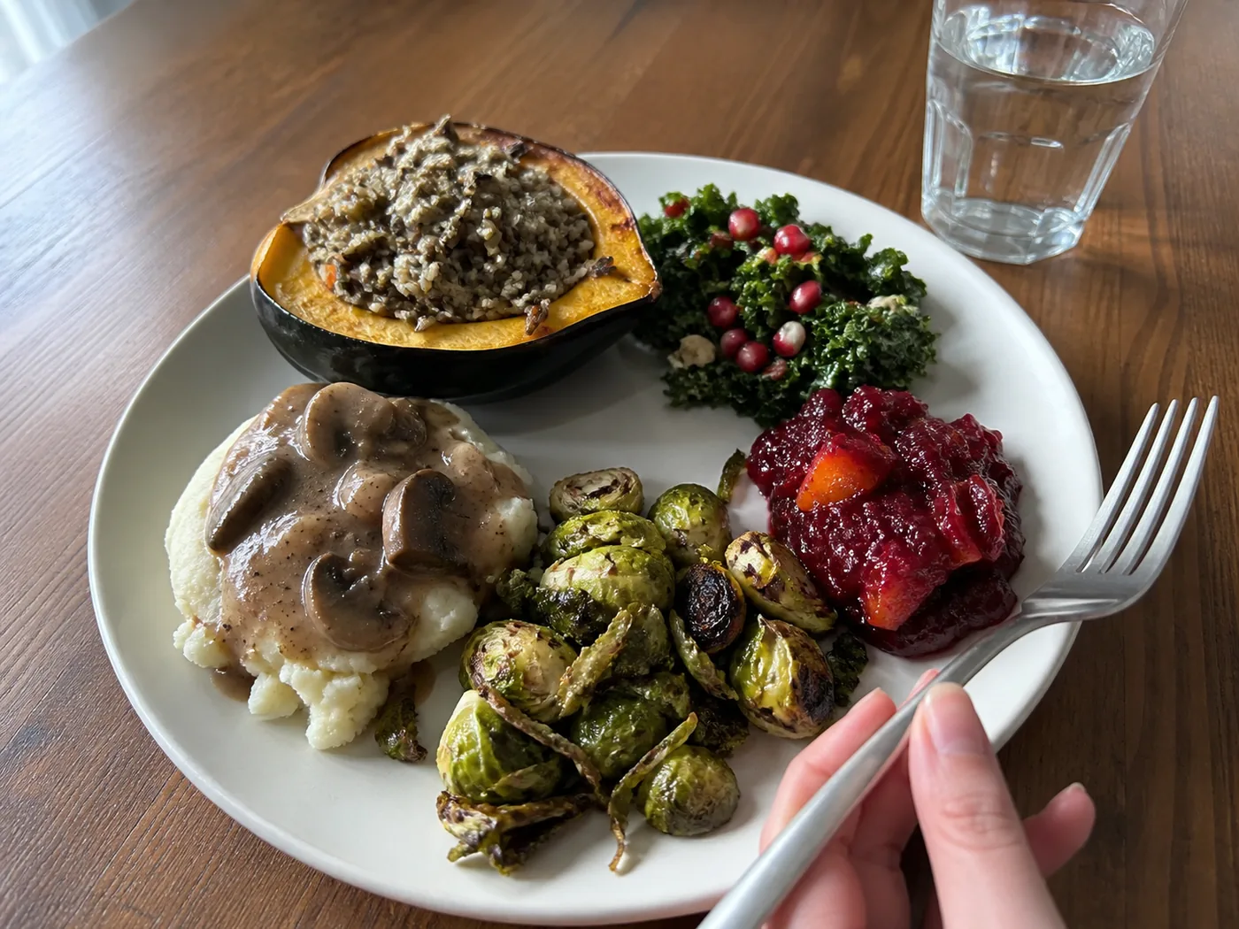 Balanced vegan Thanksgiving plate with stuffed squash, mashed potatoes, Brussels sprouts, cranberry sauce, and salad