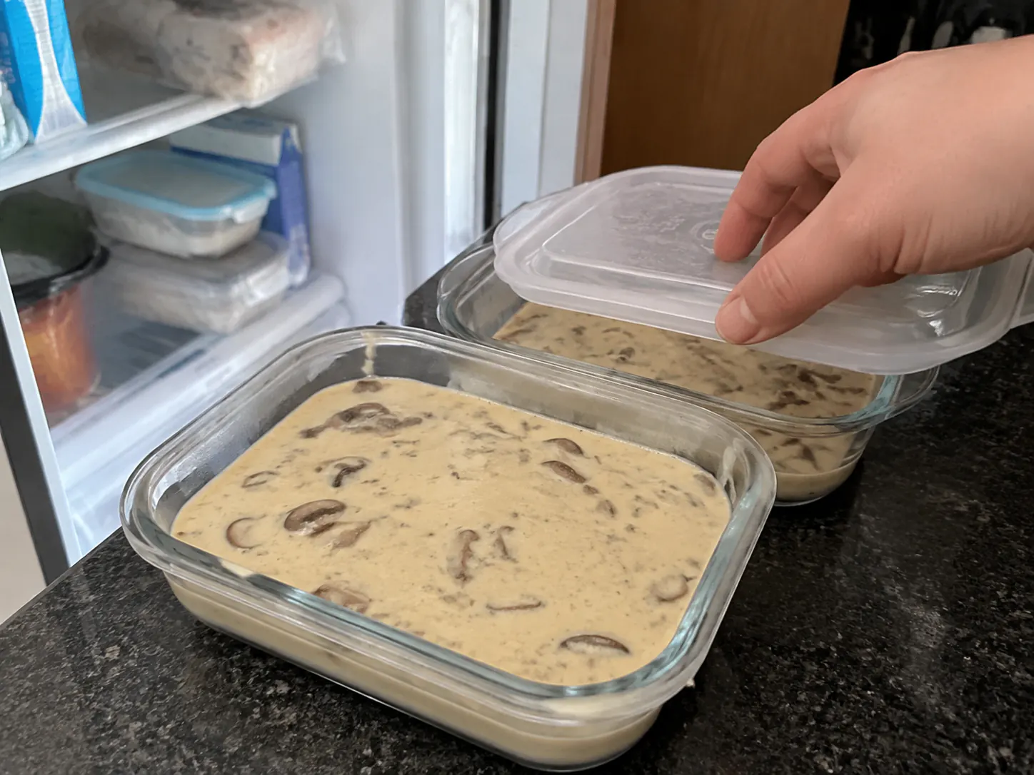 Creamy mushroom soup divided between shallow glass containers for refrigerator storage.