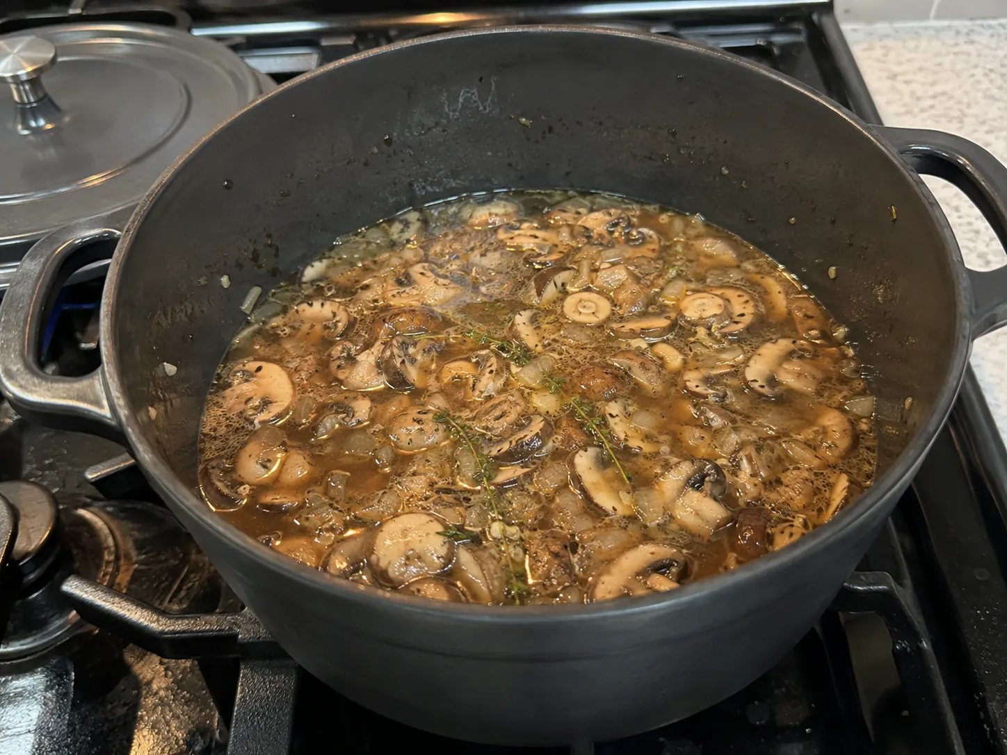 Mushrooms, onion, garlic, and thyme gently simmering in broth before the soup is blended.
