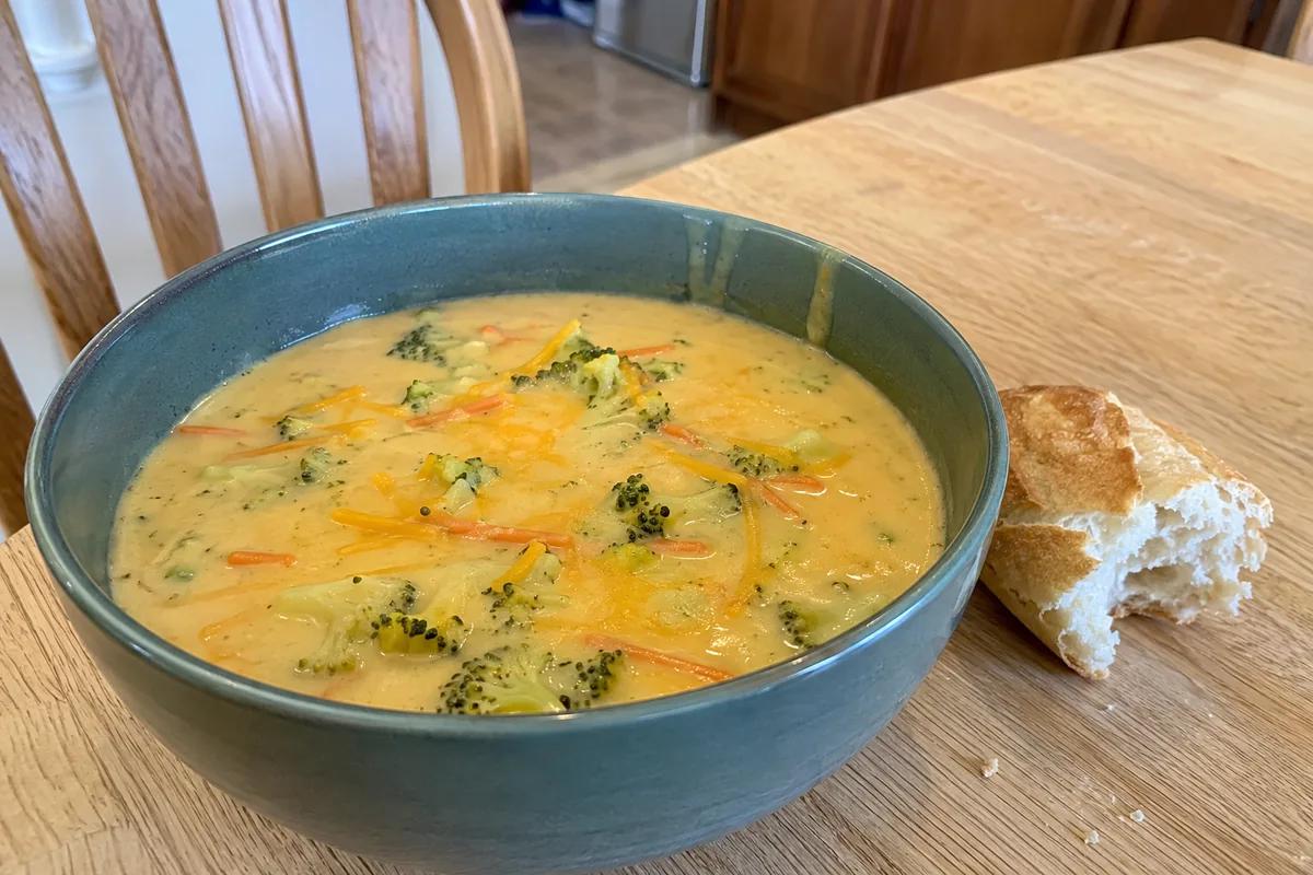Creamy broccoli cheddar soup with broccoli florets, carrot, shredded cheddar, and crusty bread.