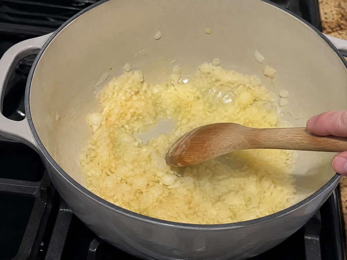 Chopped onion softening in melted butter in a Dutch oven for broccoli cheddar soup.