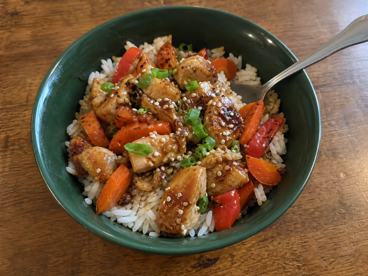 Honey sesame chicken with jasmine rice, roasted carrots and peppers, sesame seeds and green onion.