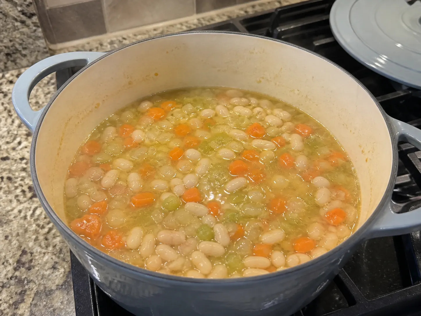Cannellini beans, carrots, celery, and onion simmering in vegetable broth before blending.